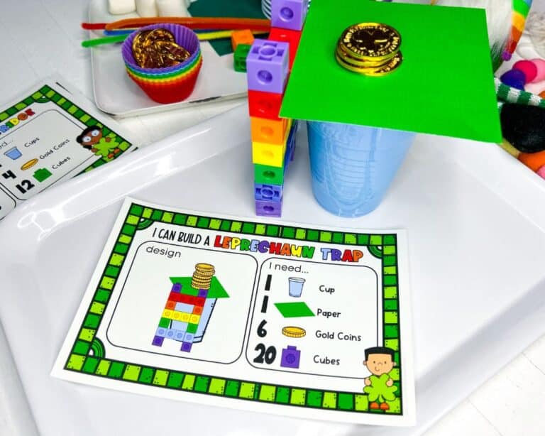 a leprechaun trap stem card along with the built leprechaun trap made from snap cubes, gold coins, paper. plastic cups.